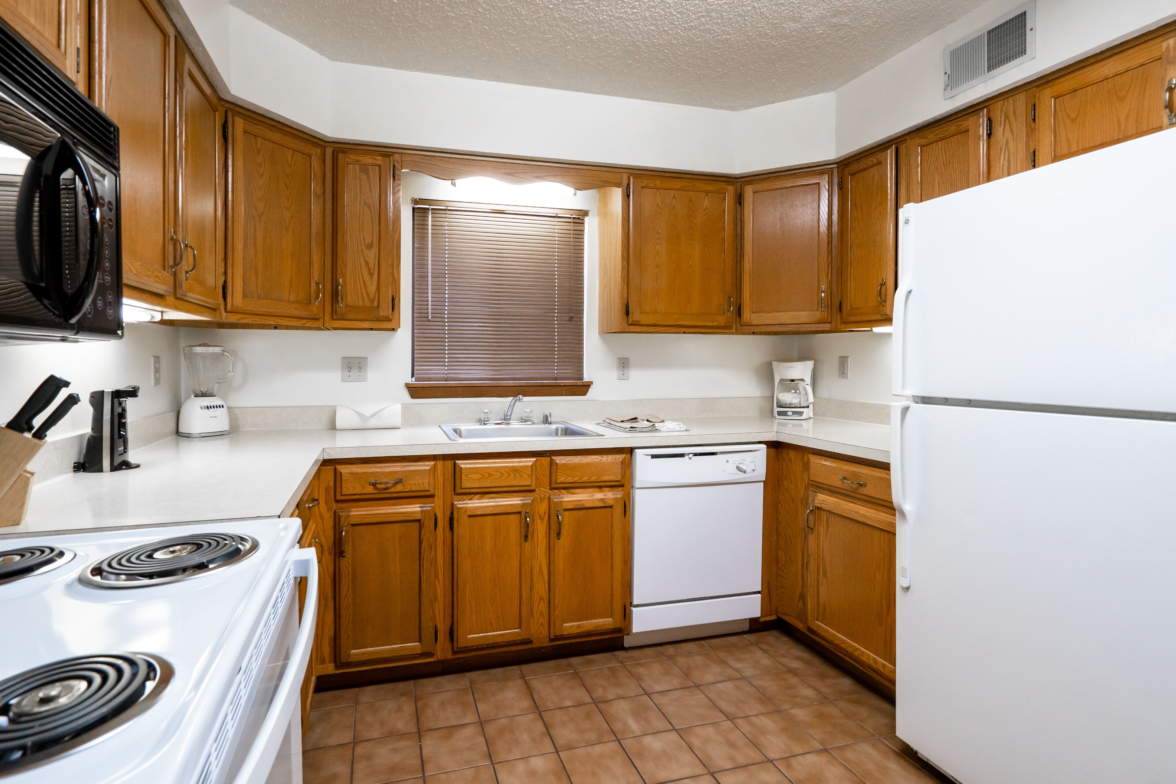 Una cocina con armarios de madera, una estufa blanca, lavavajillas y refrigerador.