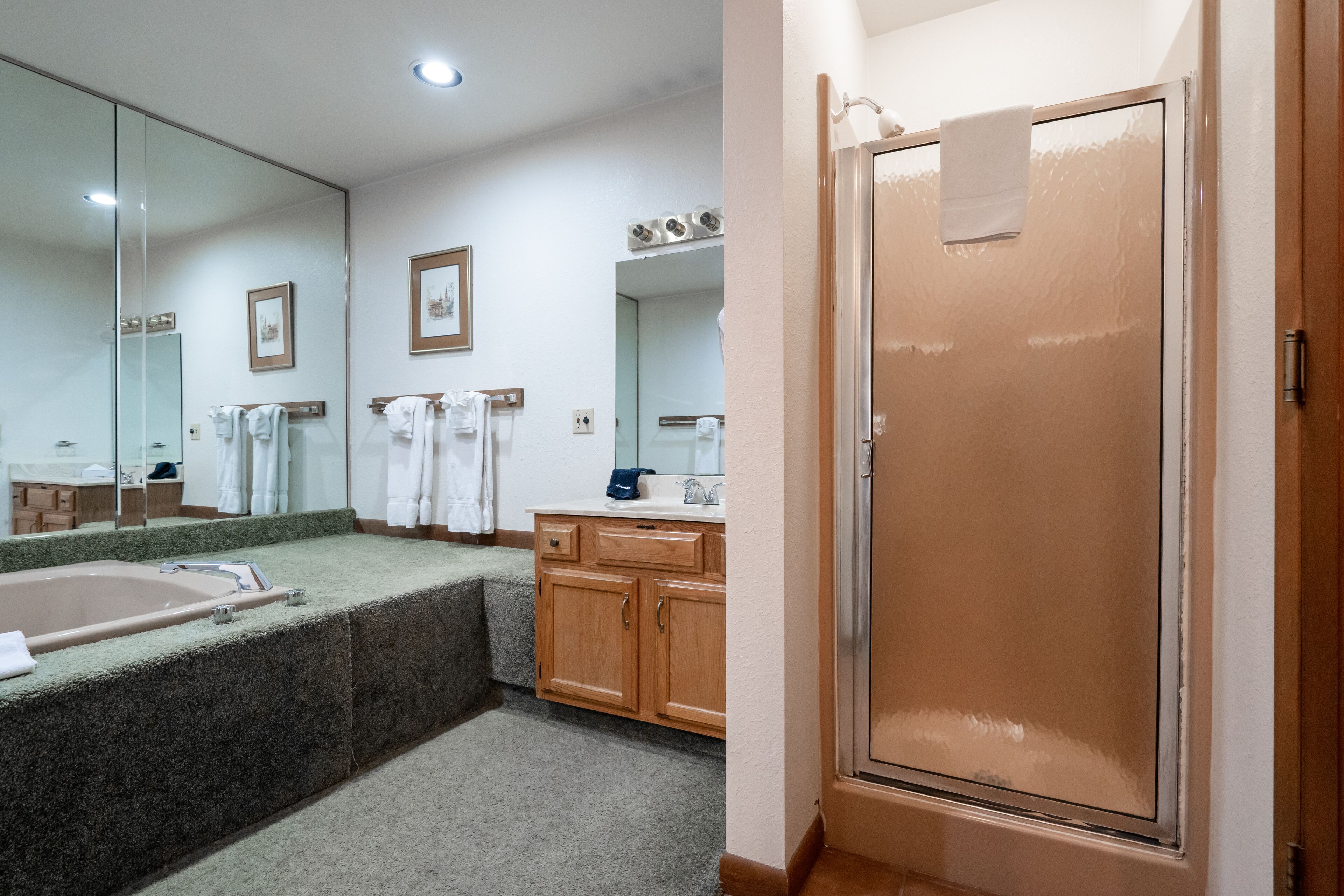 Un baño con bañera, lavamanos, espejo y mampara de ducha.
