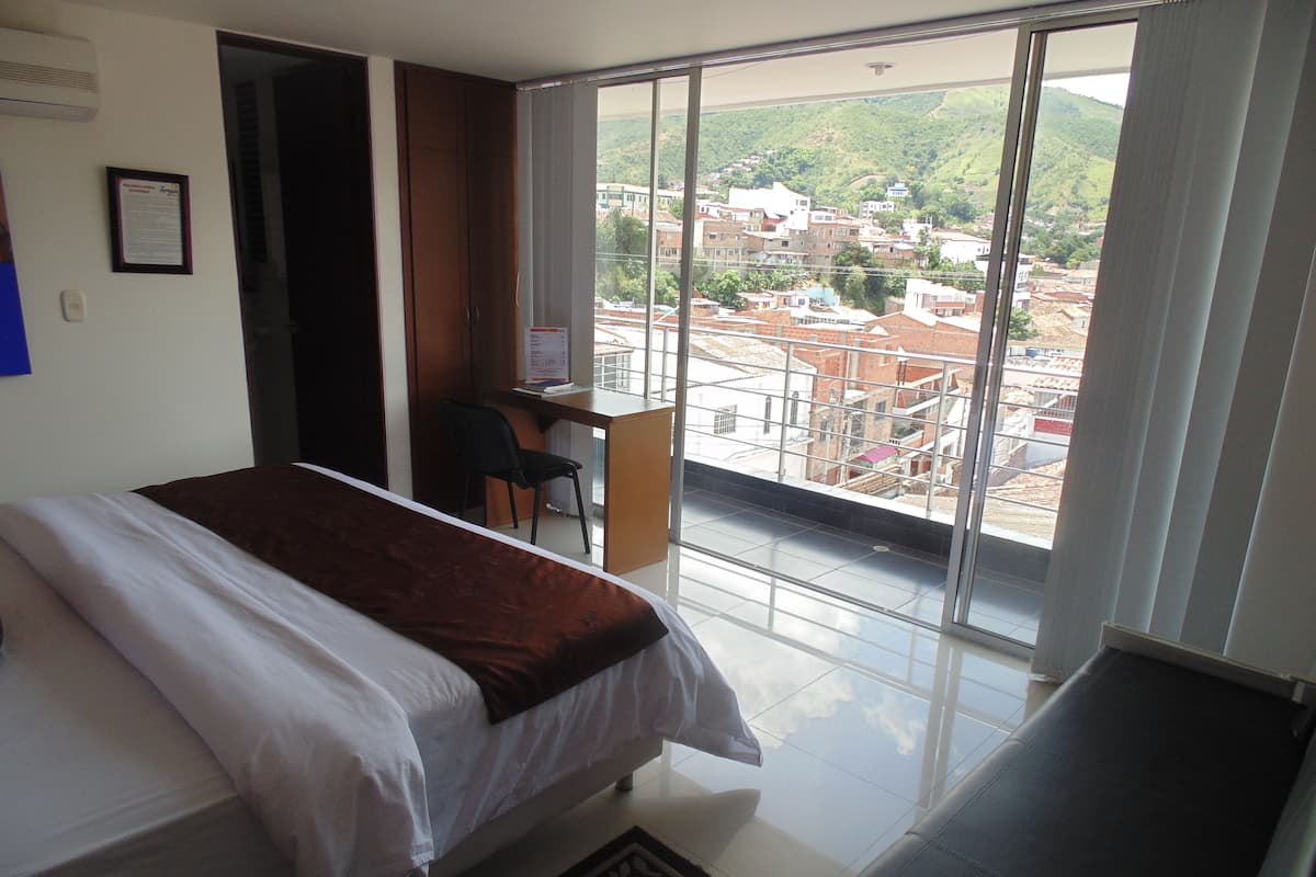 Een hotelkamer met een bed, een bureau en uitzicht op een stadsbeeld.