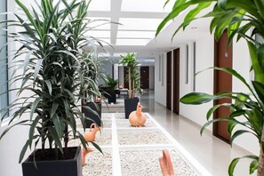 Un couloir d’hôtel moderne, agrémenté de plantes en pot et doté d’un sol carrelé.