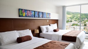 Ein Hotelzimmer mit zwei Betten, einem großen Fenster und Blick auf eine Stadtlandschaft sowie einer Wand mit farbenfroher Blumenkunst.