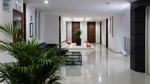 Eine moderne Hotelhalle mit einer langen Korridor, einem Empfangstresen und einer Zimmerpflanze.