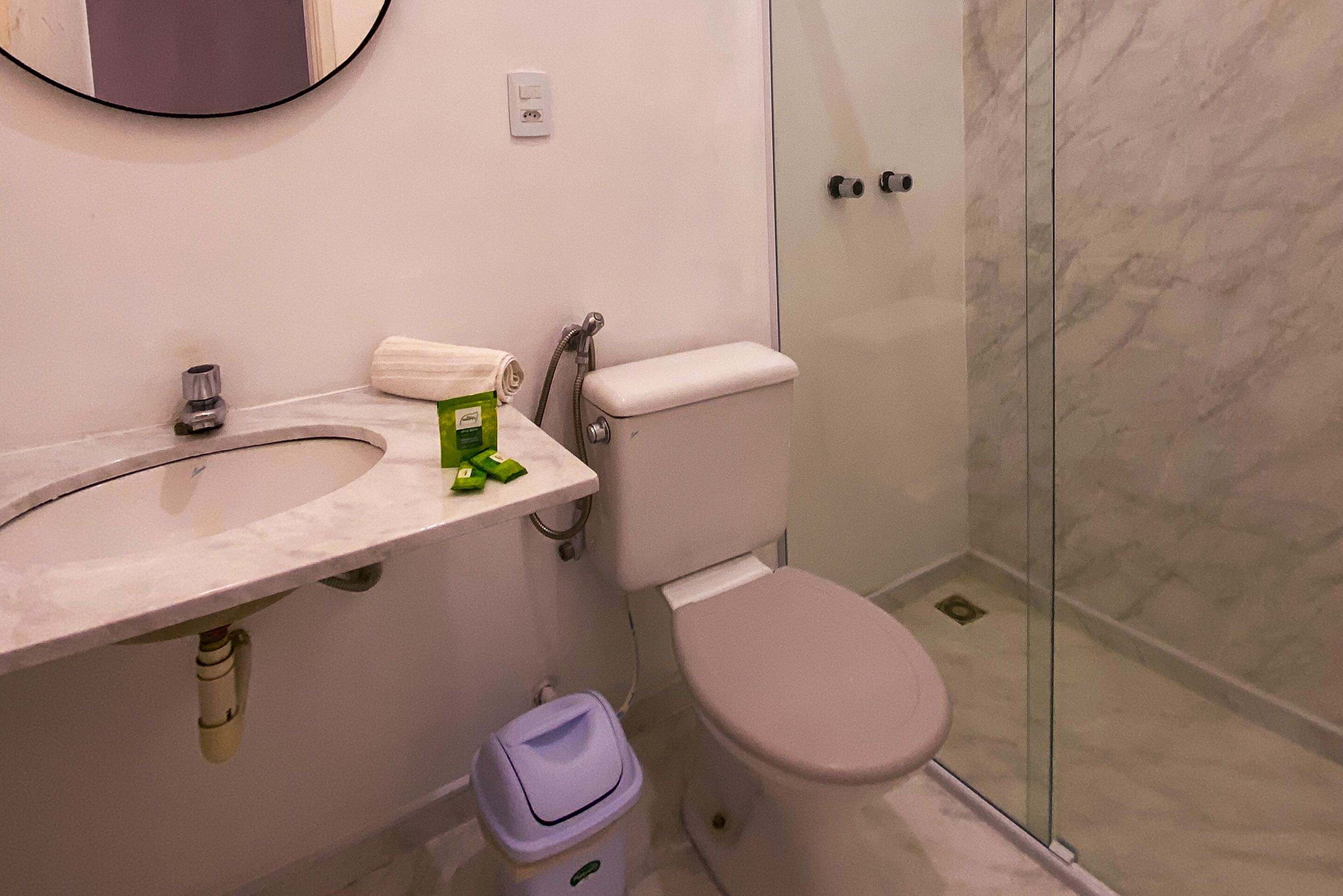 A bathroom with a marble sink, a toilet, and a glass shower enclosure.