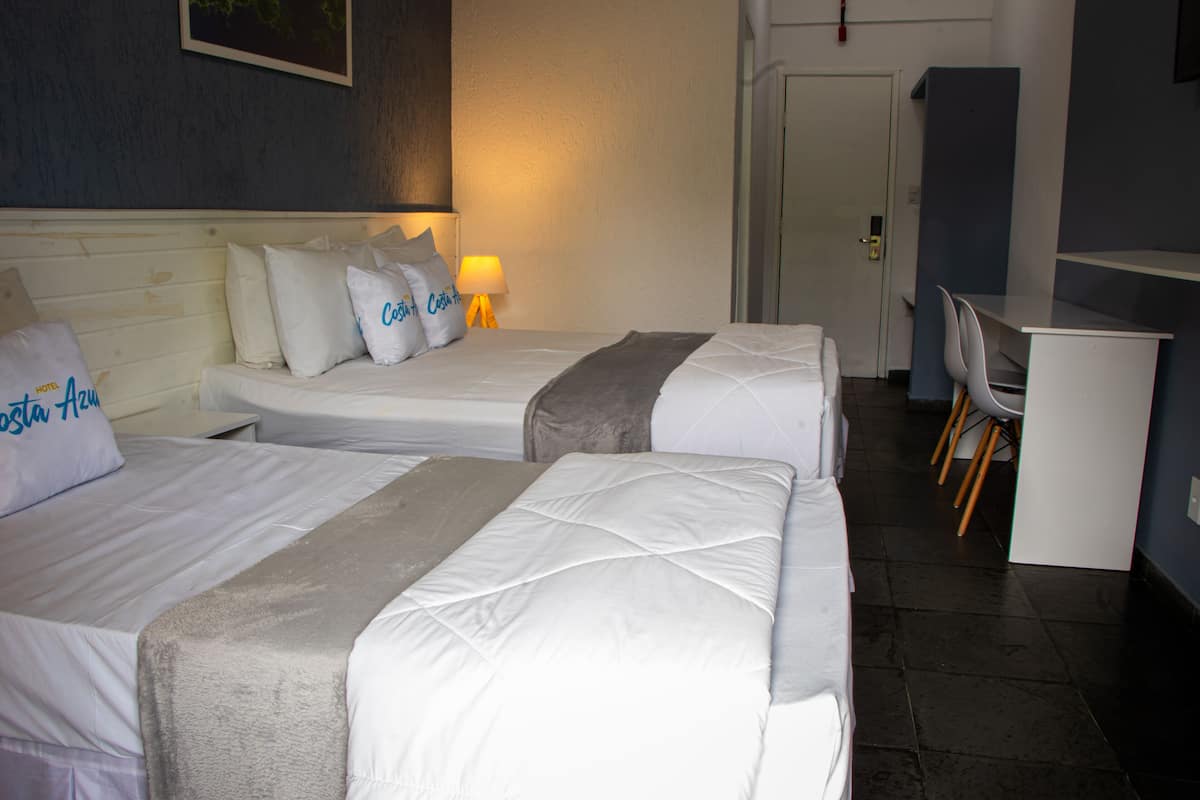 Habitación de hotel con dos camas, un escritorio y una silla.