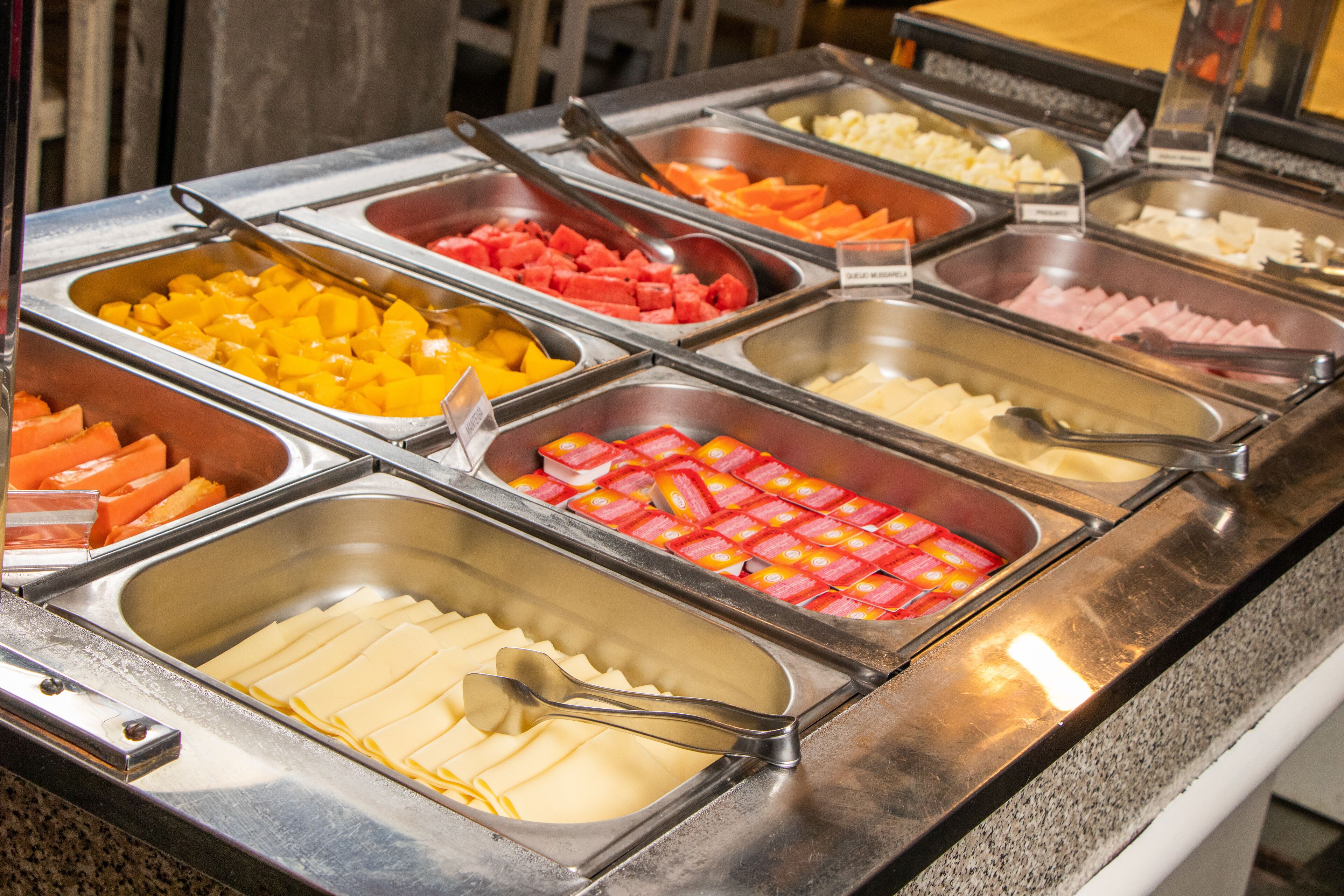 A buffet with various food items including fruits, vegetables, and cheeses.