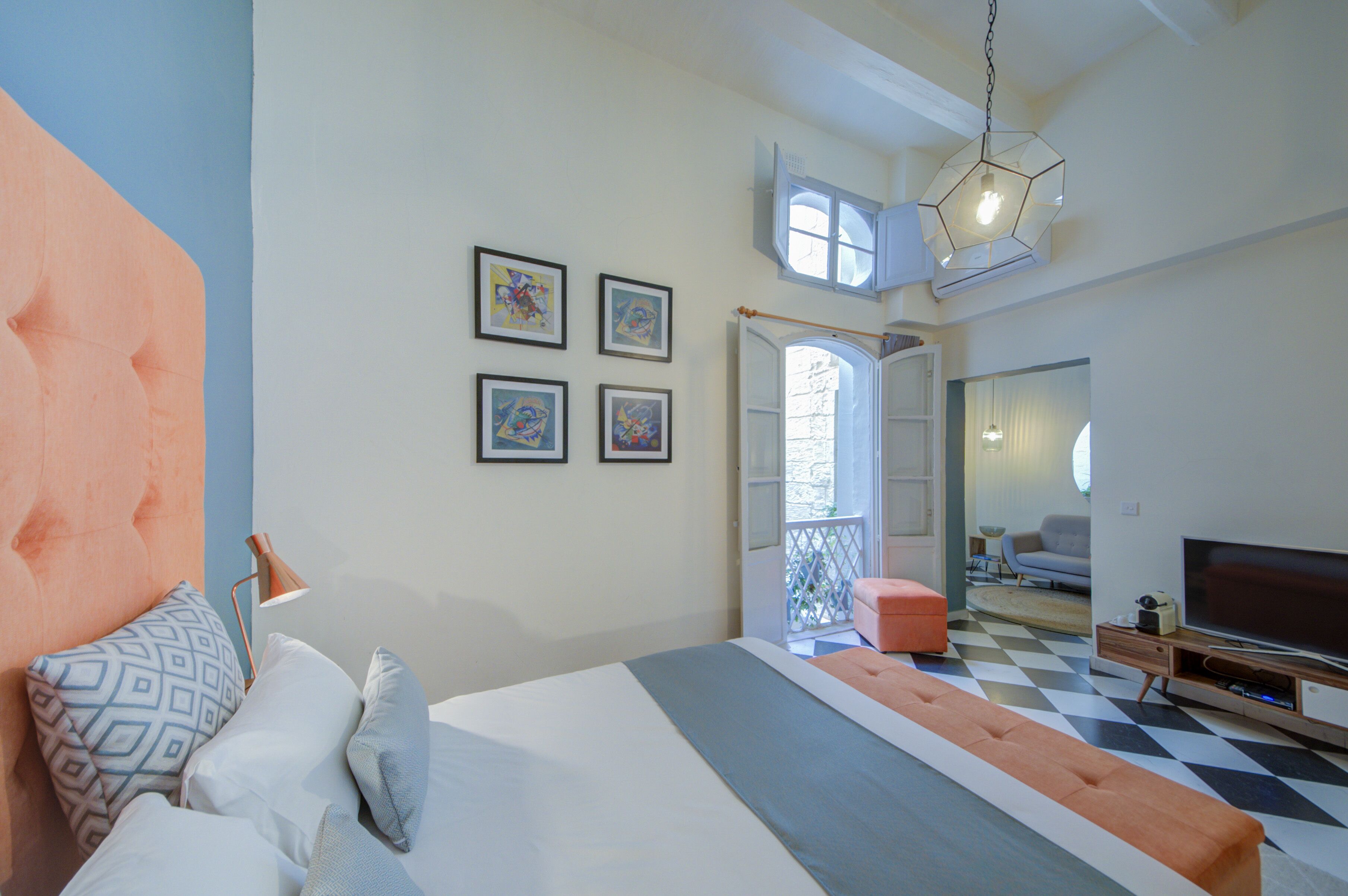 Un dormitorio moderno con una cama grande, un televisor y un balcón.