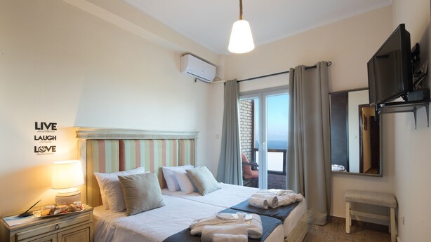 Ein Hotelzimmer mit Bett, Nachttisch, Lampe und einem an der Wand befestigten Fernseher.