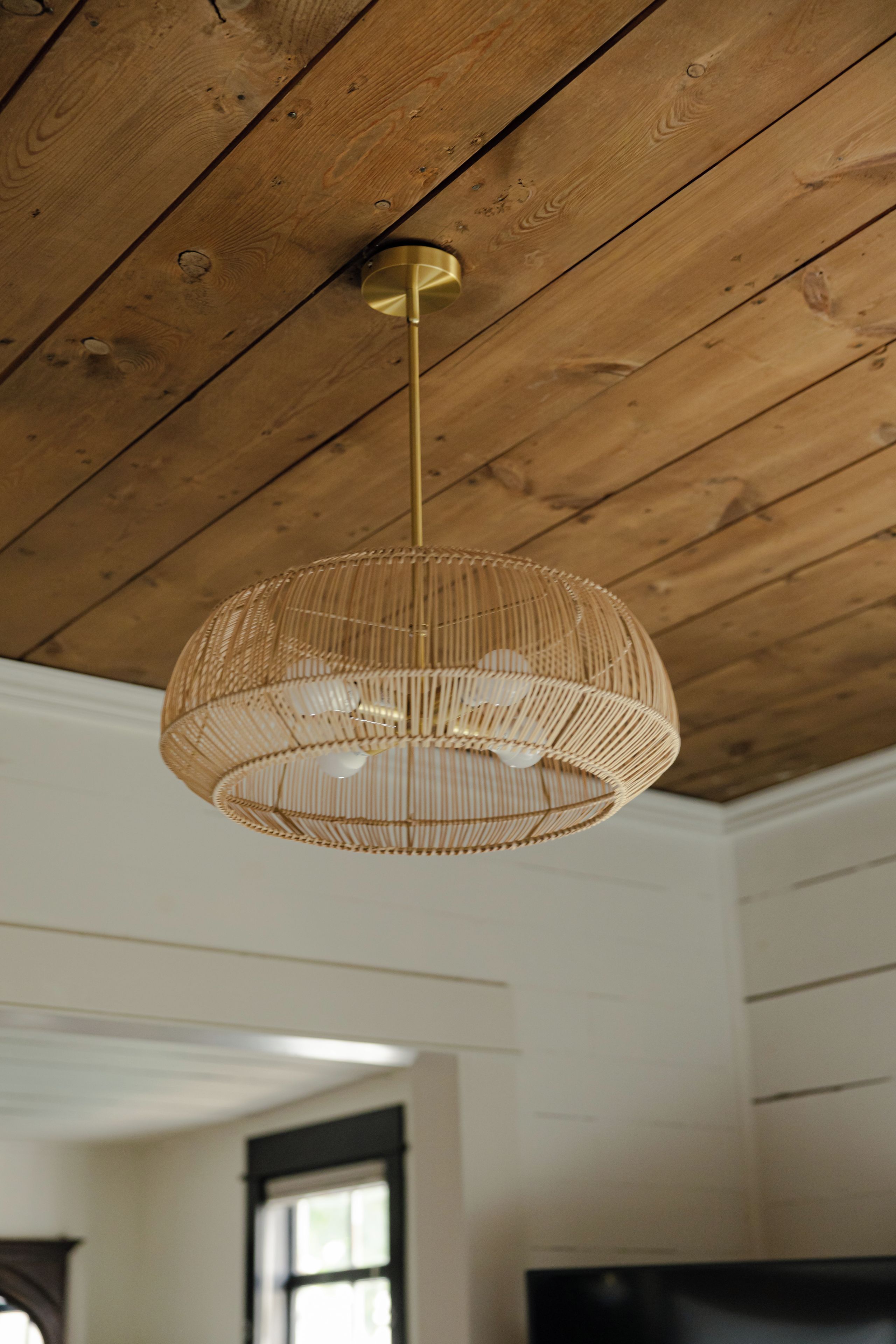 Una stanza con soffitto in legno e lampadario pendente in vimini.