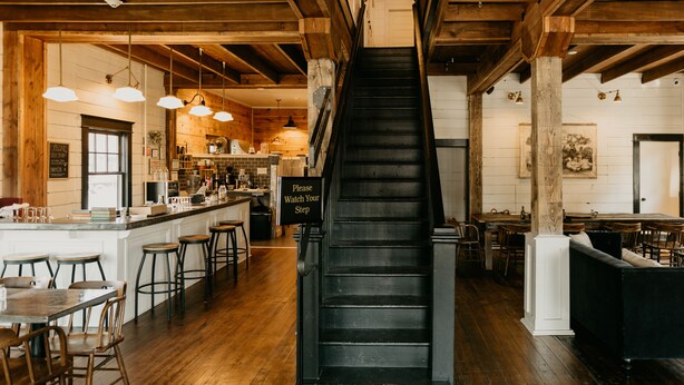 A staircase in a wooden interior with a bar area on the left and seating on the right. - The Landing Hotel and Dining (La Grande)