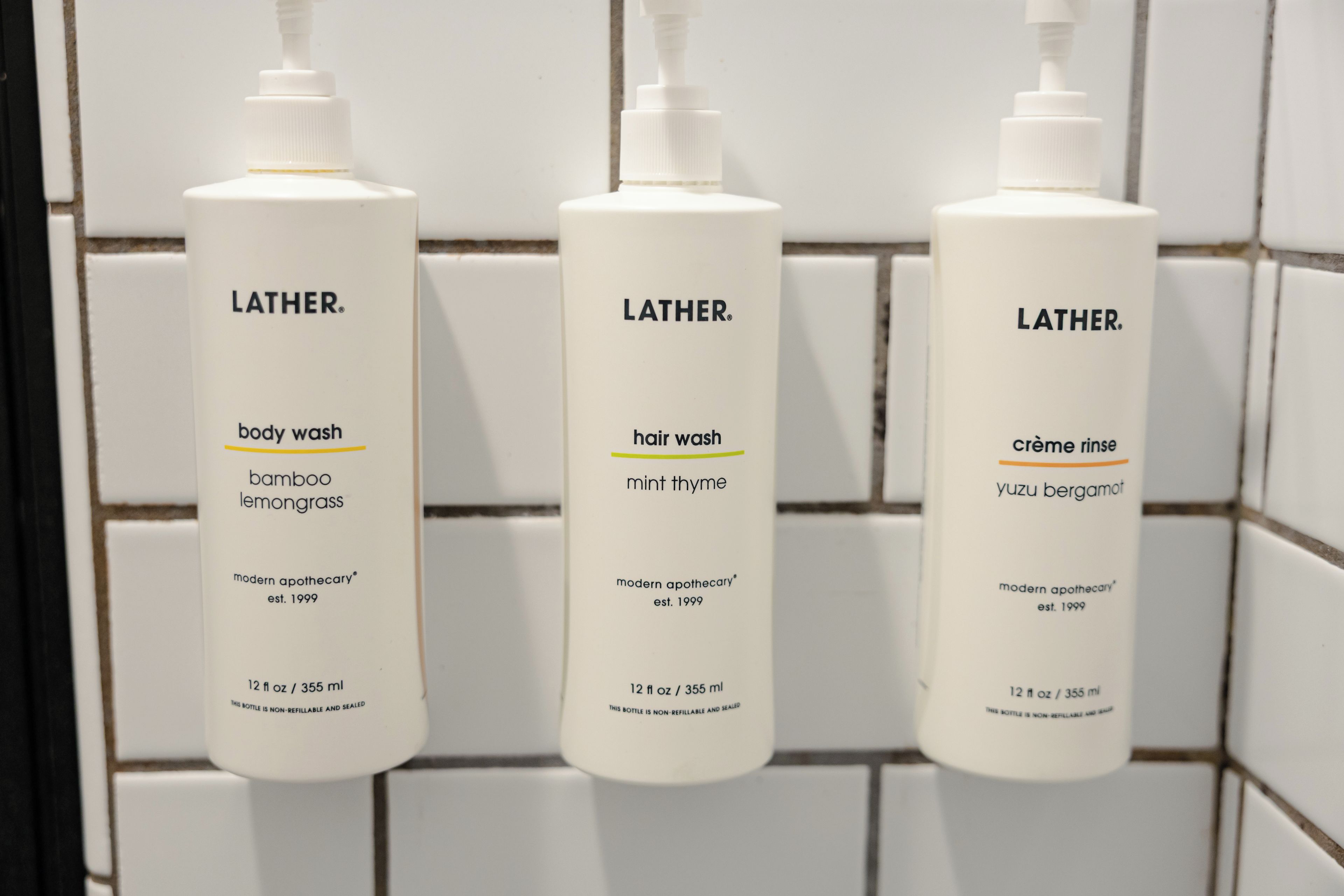 Three Lather body wash bottles in a bathroom.