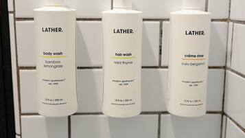 Three Lather body wash bottles in a bathroom.