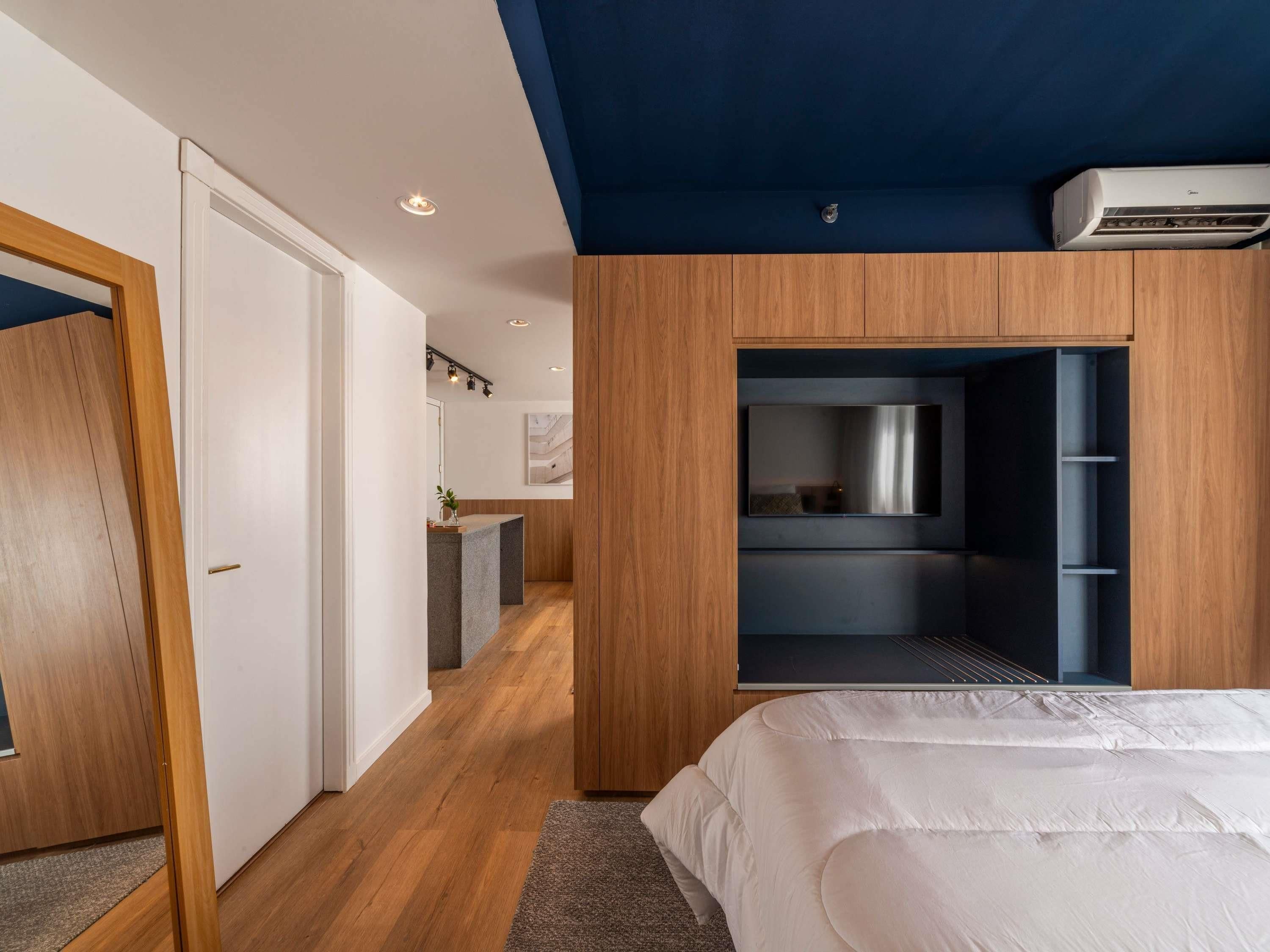 Quarto moderno com uma cama grande, armário embutido e pequena área de kitchenette.