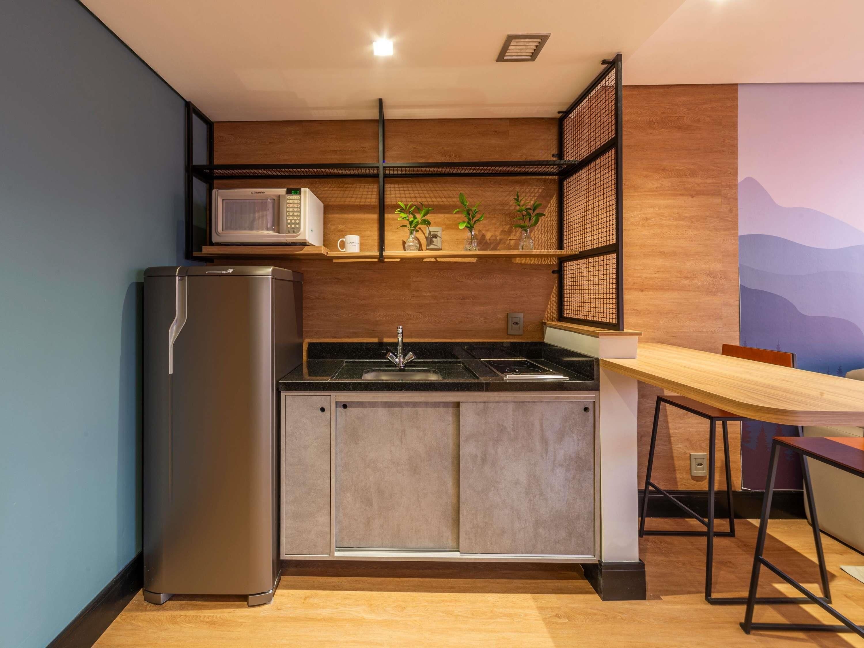 Une cuisine compacte équipée d’un réfrigérateur, d’un four à micro-ondes, d’un évier et d’un coin repas avec une table et des chaises.