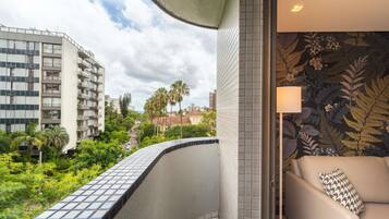 A balcony with a tiled floor, a sofa with a patterned pillow, and a wall with a floral wallpaper.