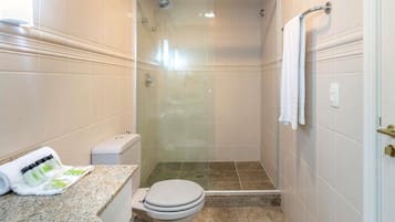 A bathroom with a toilet, shower, and granite countertop.