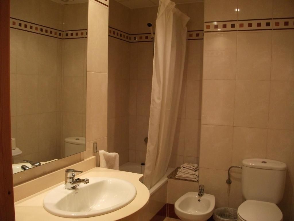 Ein Badezimmer mit Waschbecken, Bidet, Toilette und Duschvorhang.