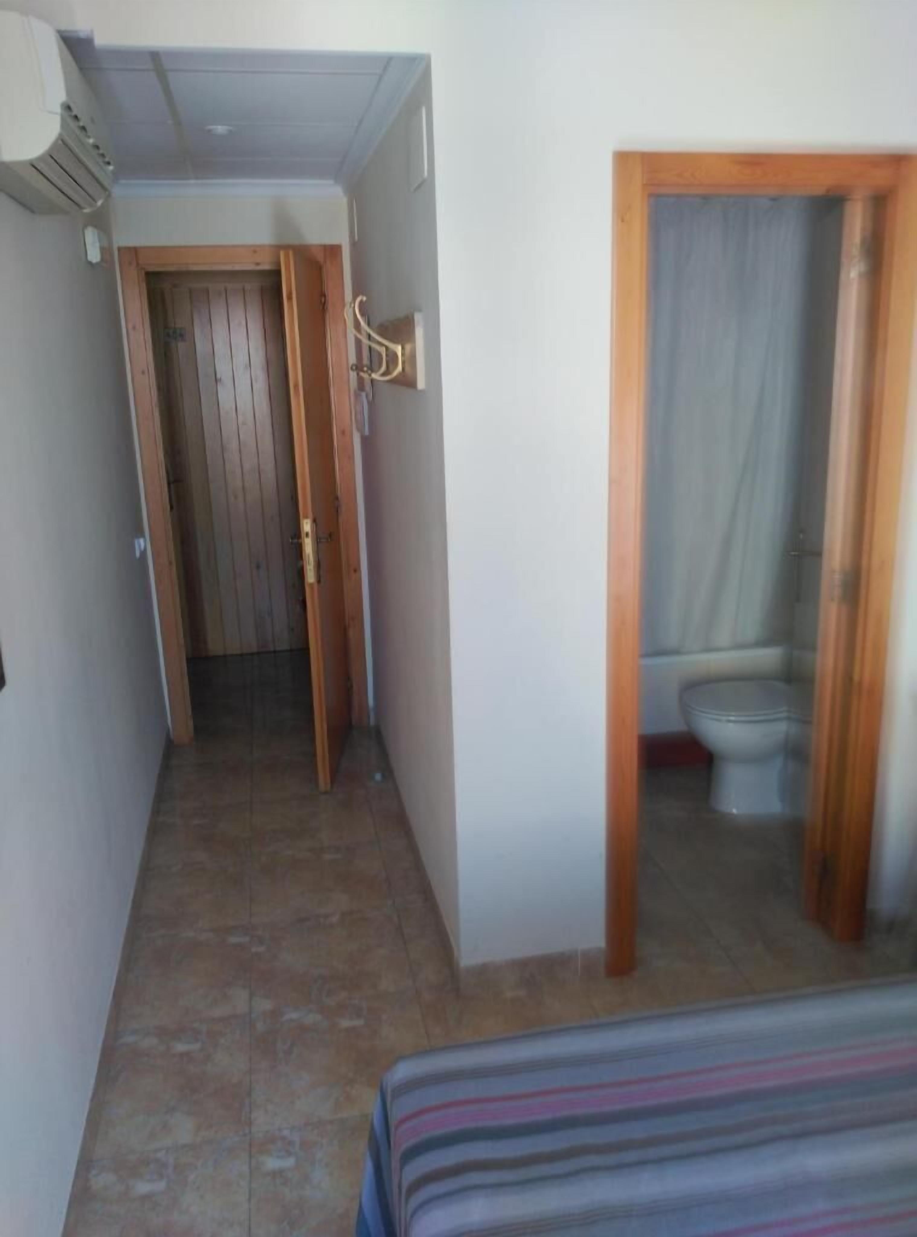 A narrow hallway leading to a bathroom with a toilet and shower.