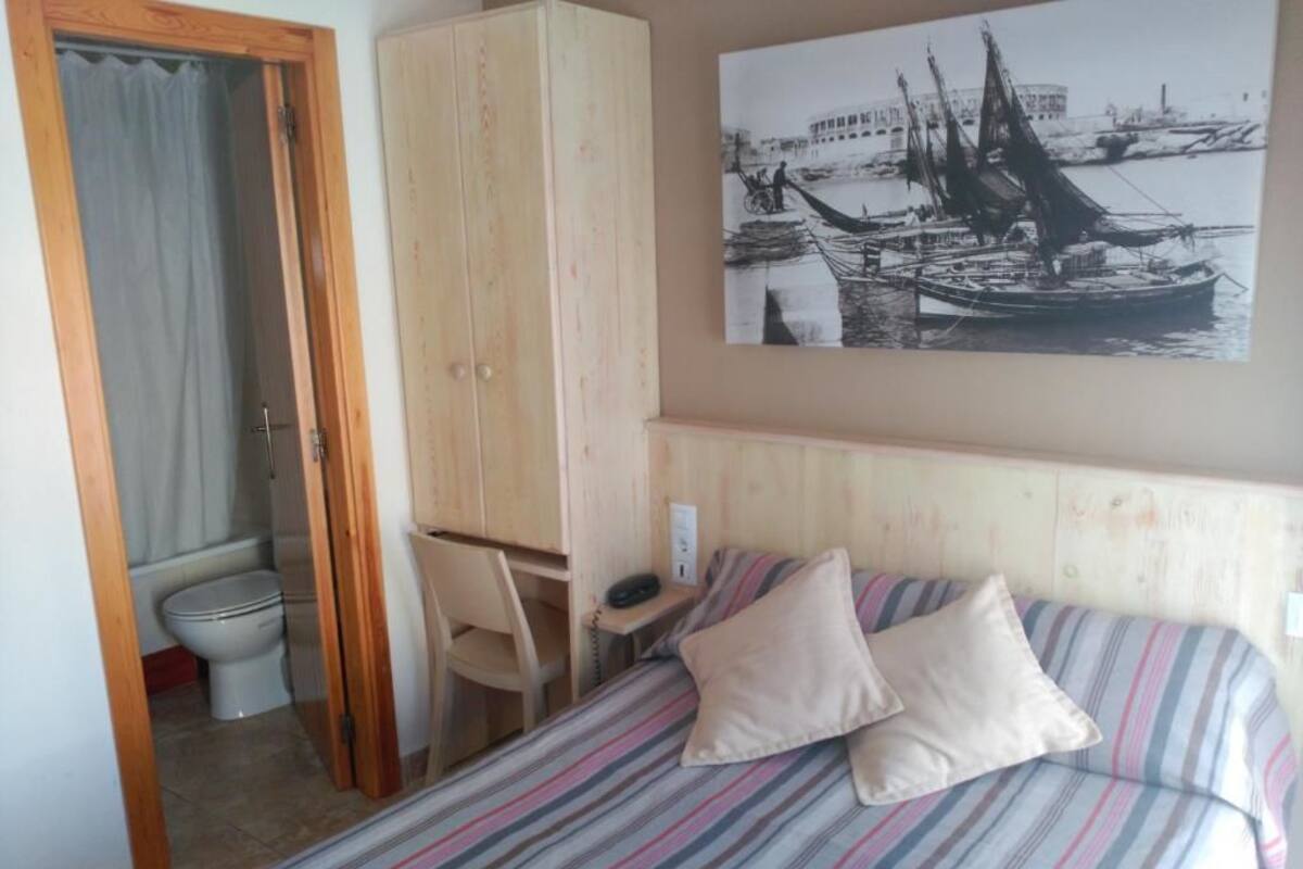Habitació d'hotel amb llit, escriptori, cadira i armari.