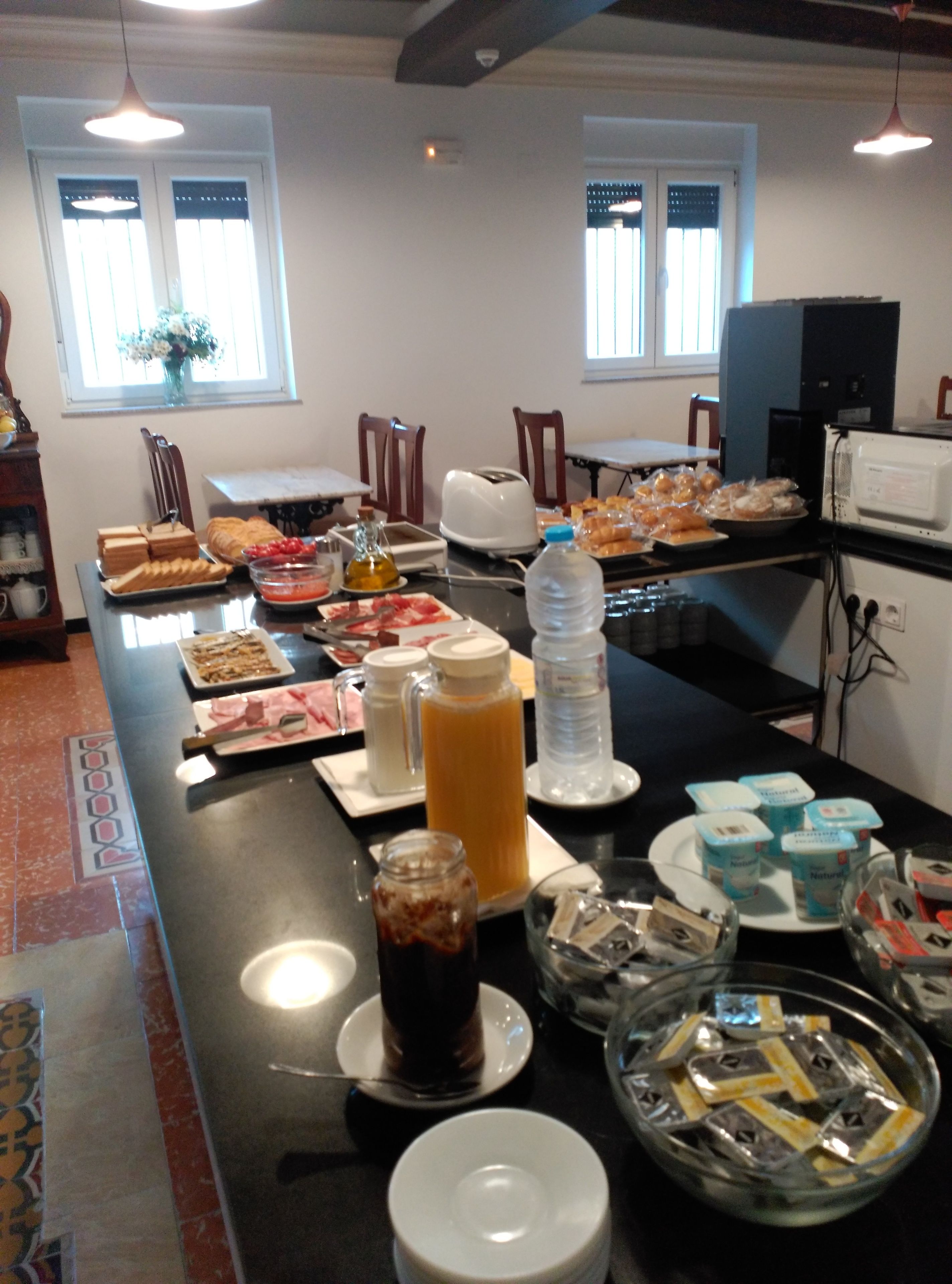 Una mesa de buffet con diferentes alimentos, un dispensador de agua y un microondas.