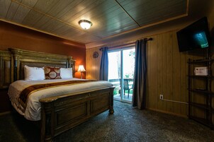 Un dormitorio con una cama grande, un televisor en la pared y un ventanal corredero que da a un espacio exterior.