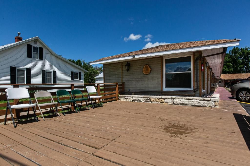 A wooden deck with chairs, a building with a large window, and a vehicle parked nearby.