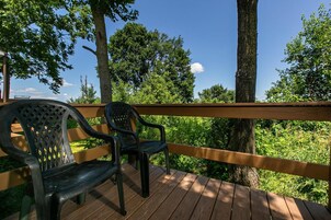 Una terraza de madera con dos sillas de plástico negro y una barandilla de madera.