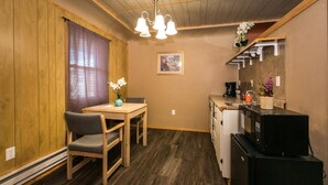 A compact kitchen with a dining table and chairs, a refrigerator, and a microwave. - The Wisconsin Wood Inn (Dickeyville)