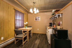 A compact kitchen with a dining table and chairs, a refrigerator, and a microwave. - The Wisconsin Wood Inn (Dickeyville)