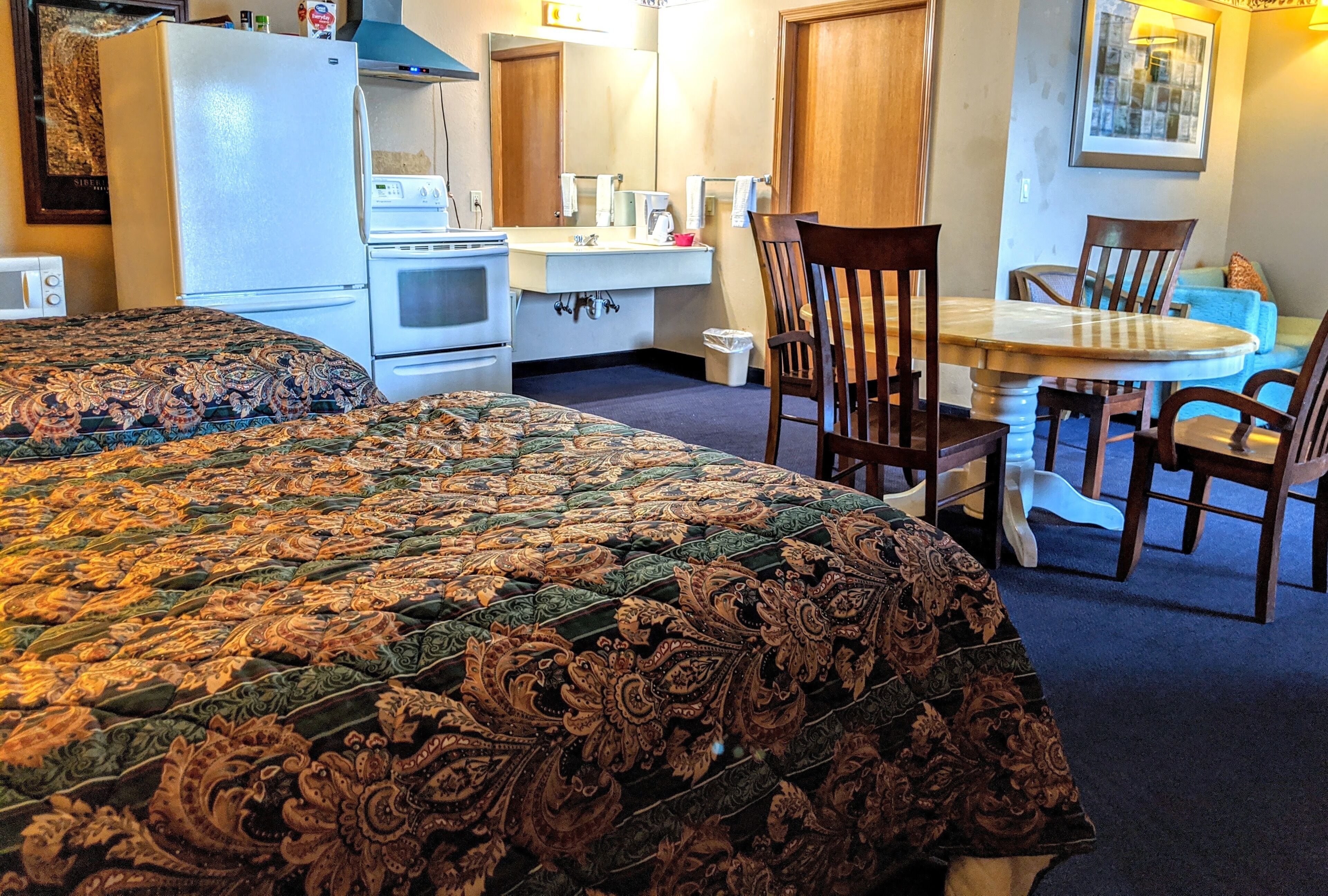 Een hotelkamer met een groot bed, een eettafel met stoelen, een kitchenette en een badkamer.