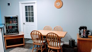 A dining area with a wooden table and chairs, a clock on the wall, a vending machine, and a coffee maker. - Executive Inn Thomson (Thomson)