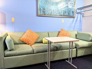 A green sofa with patterned cushions, a small table, and a painting on the wall. - Executive Inn Thomson (Thomson)