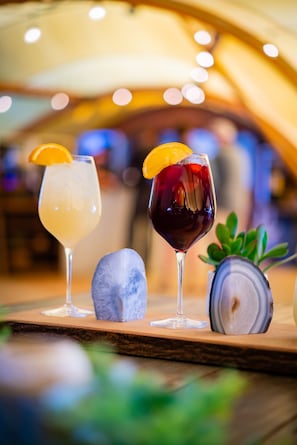Three glasses of beverages on a wooden surface with a decorative rock and a plant.