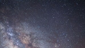 Ein Zelt unter einem Sternenhimmel, zwei Personen stehen davor.