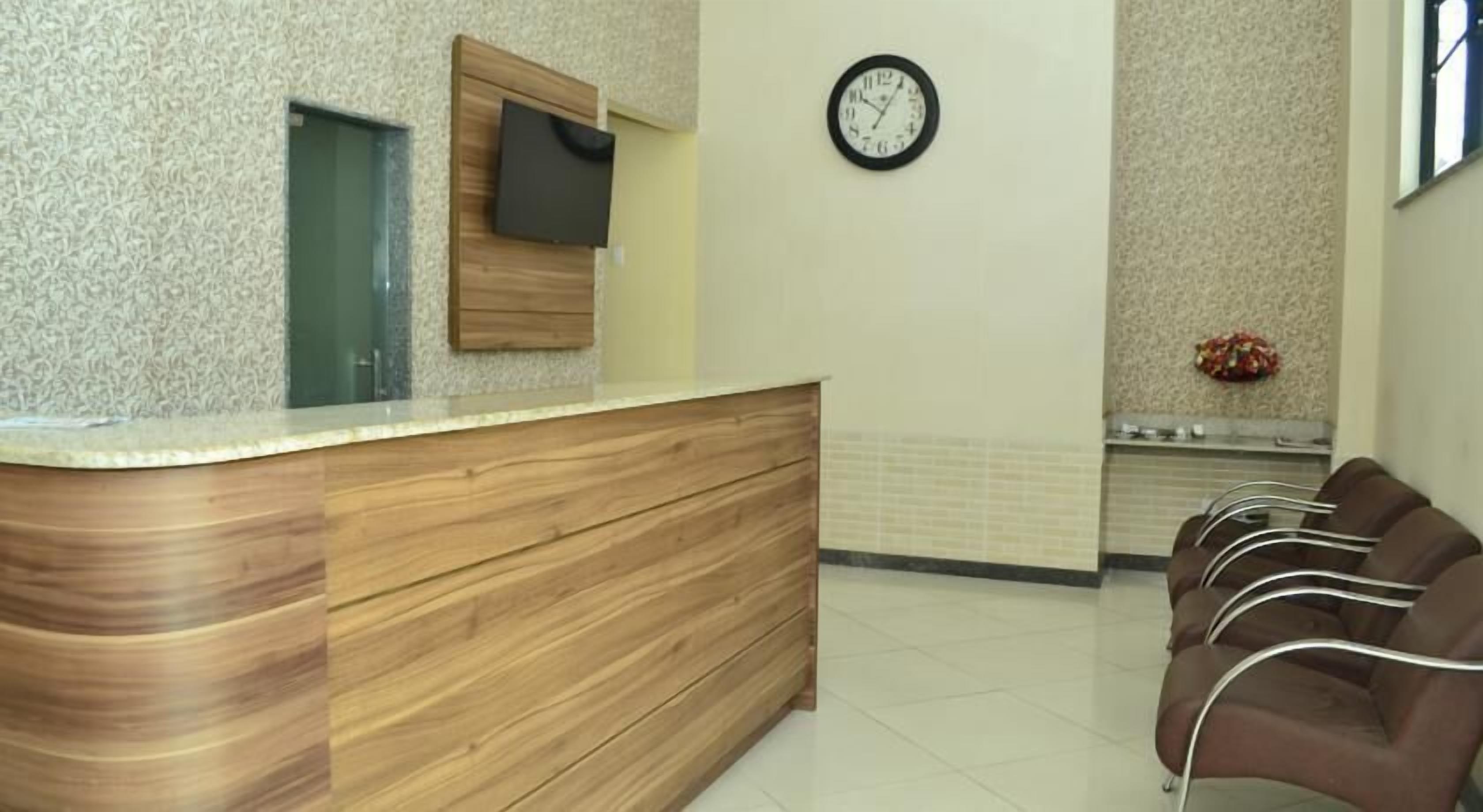 A reception area with a wooden counter, a clock, and a seating area with chairs.