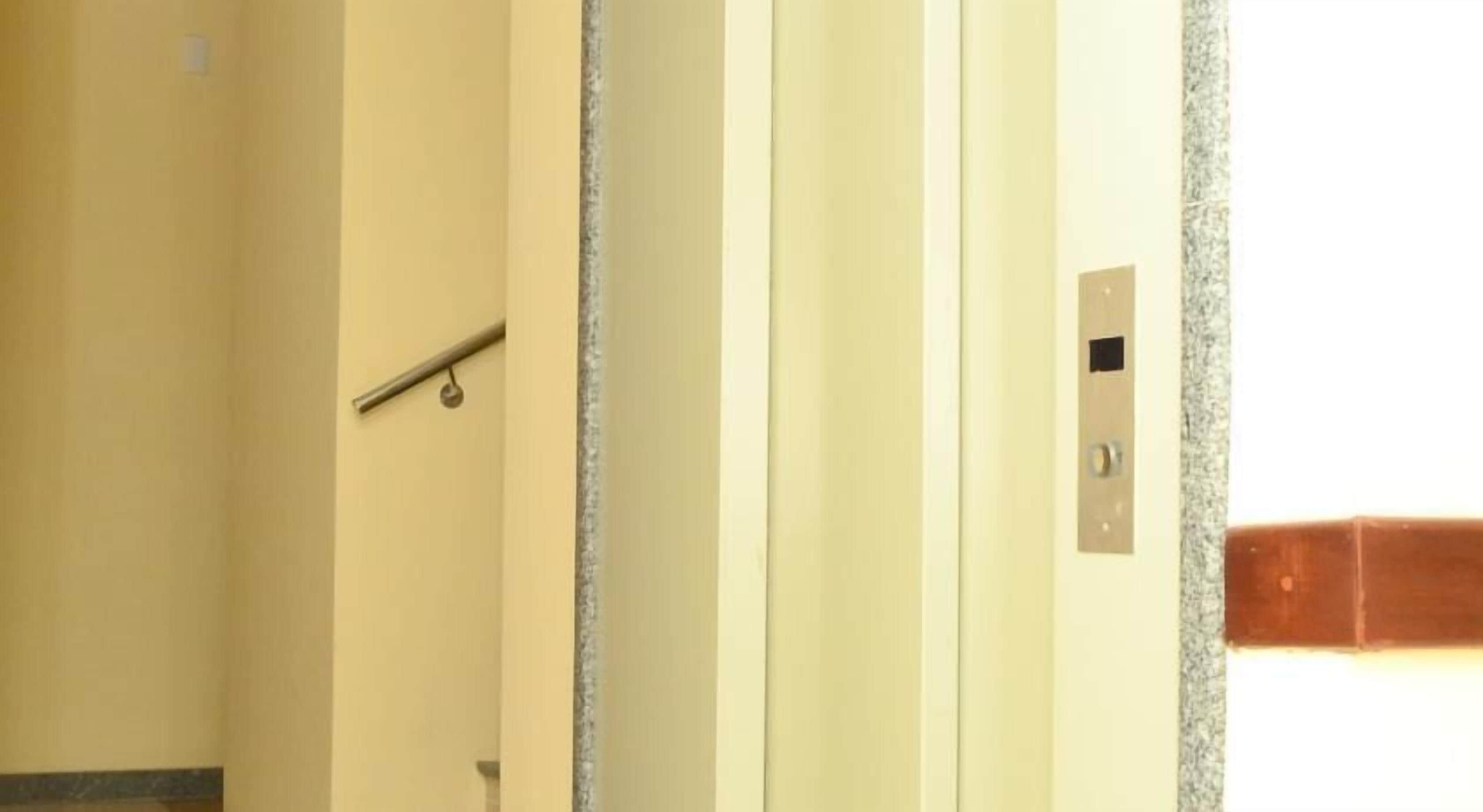 An elevator interior with a handrail, a control panel, and a door.
