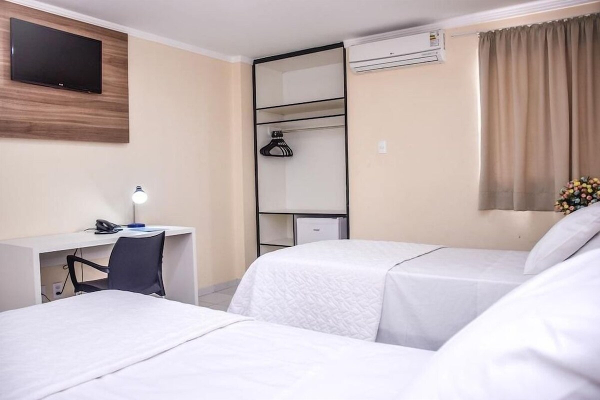 Une chambre d’hôtel comprenant un lit, un bureau, une chaise, une télévision et une armoire.