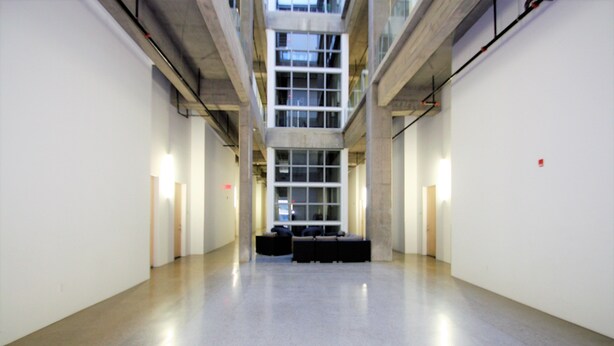 A spacious, modern interior with a high ceiling, a central seating area, and a view through large windows. - Downtown Executive Condo Loft (Saskatoon)