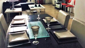 A dining area with a table set for four, a television, and a refrigerator in the background. - Downtown Executive Condo Loft (Saskatoon)