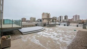 A rooftop terrace with a view of the city skyline, featuring a mix of modern and older buildings. - Downtown Executive Condo Loft (Saskatoon)