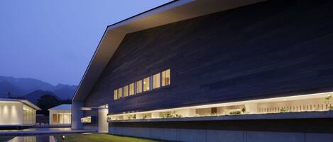 Un edificio moderno con tejado plano, ventanas amplias e iluminación exterior destacada.