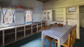 A dining area with a checkered tablecloth, wooden chairs, and a long bench. - Little Styx Cabins (Ebor)
