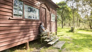 A wooden cabin with a bench outside. - Little Styx Cabins (Ebor)