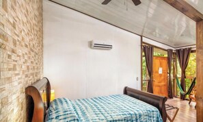 A room with a bed, an air conditioning unit, a hammock, and a view of greenery outside. - La Quinta Sarapiqui Lodge (La Virgen)