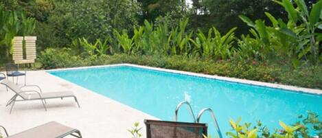 Una piscina con sillones de descanso y una terraza de madera.