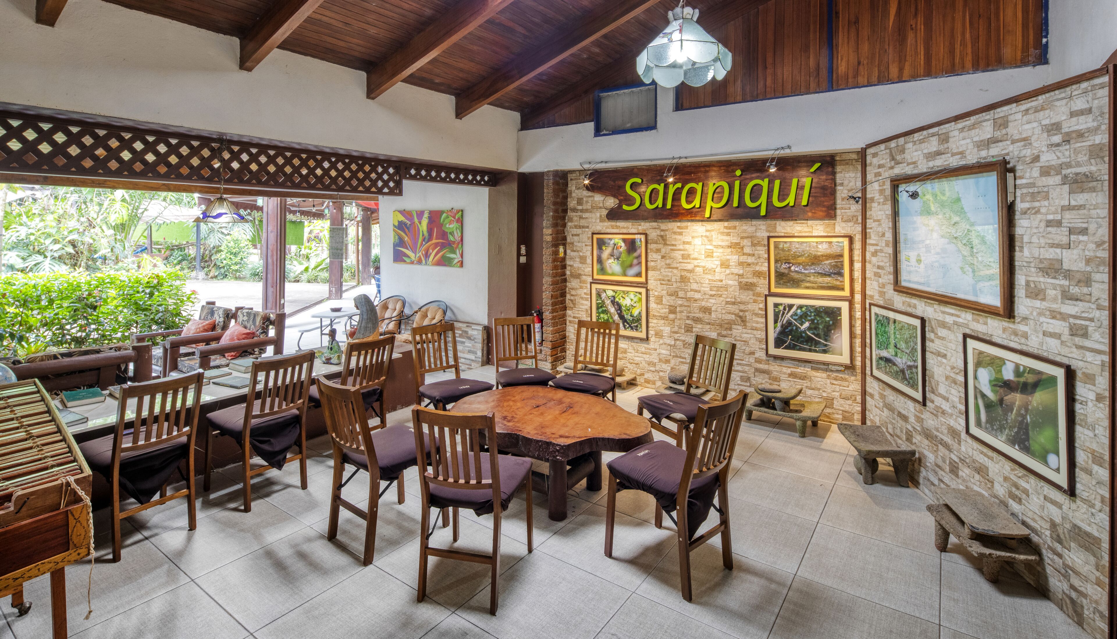 A dining area with a wooden table and chairs, surrounded by stone walls and framed pictures.