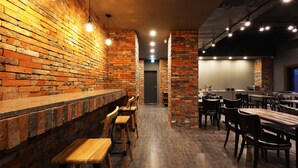 A restaurant with brick walls, wooden bar stools, and tables. - Hotel Mondavi (Mokpo)
