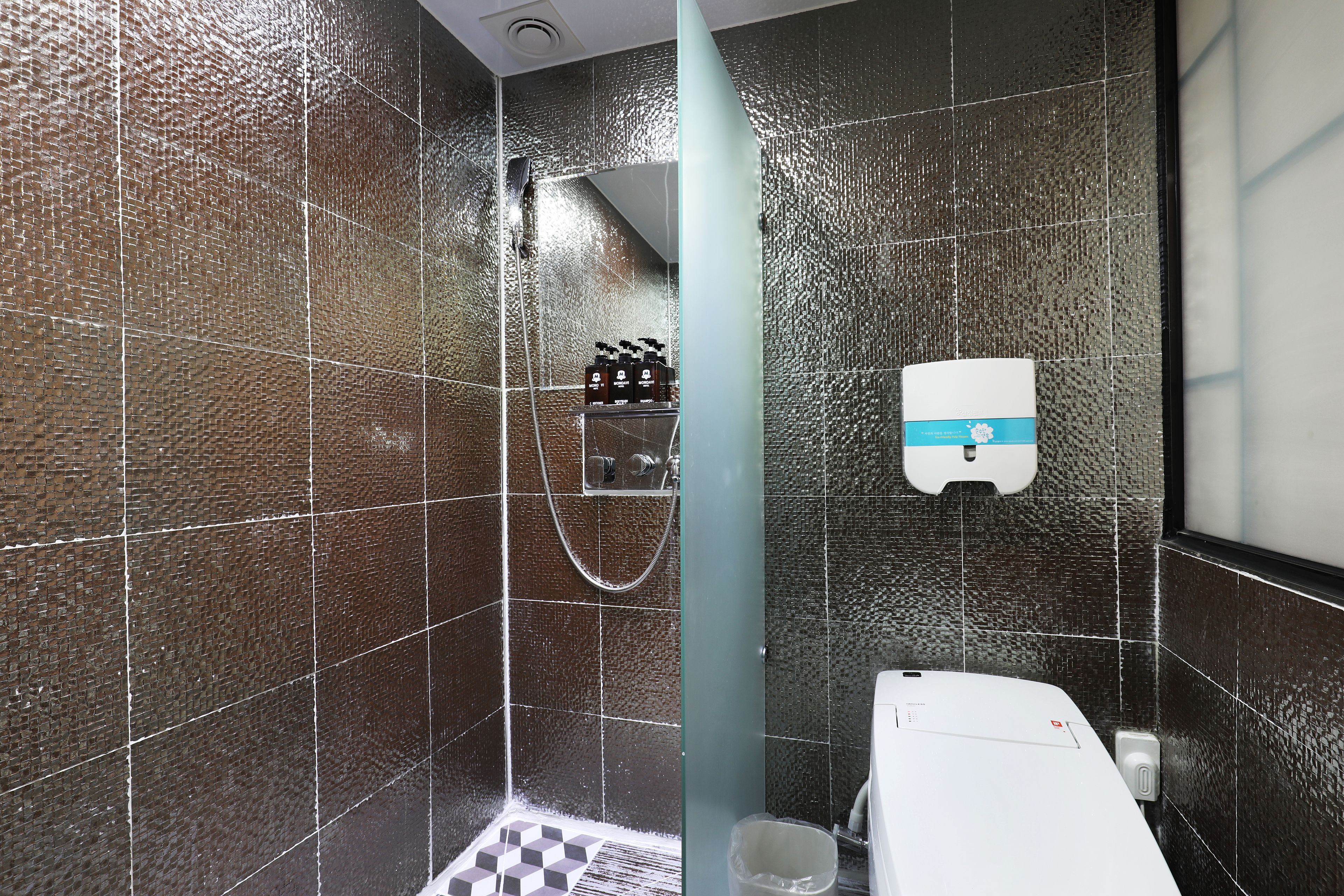 A bathroom with a shower, a toilet, and a hand dryer.