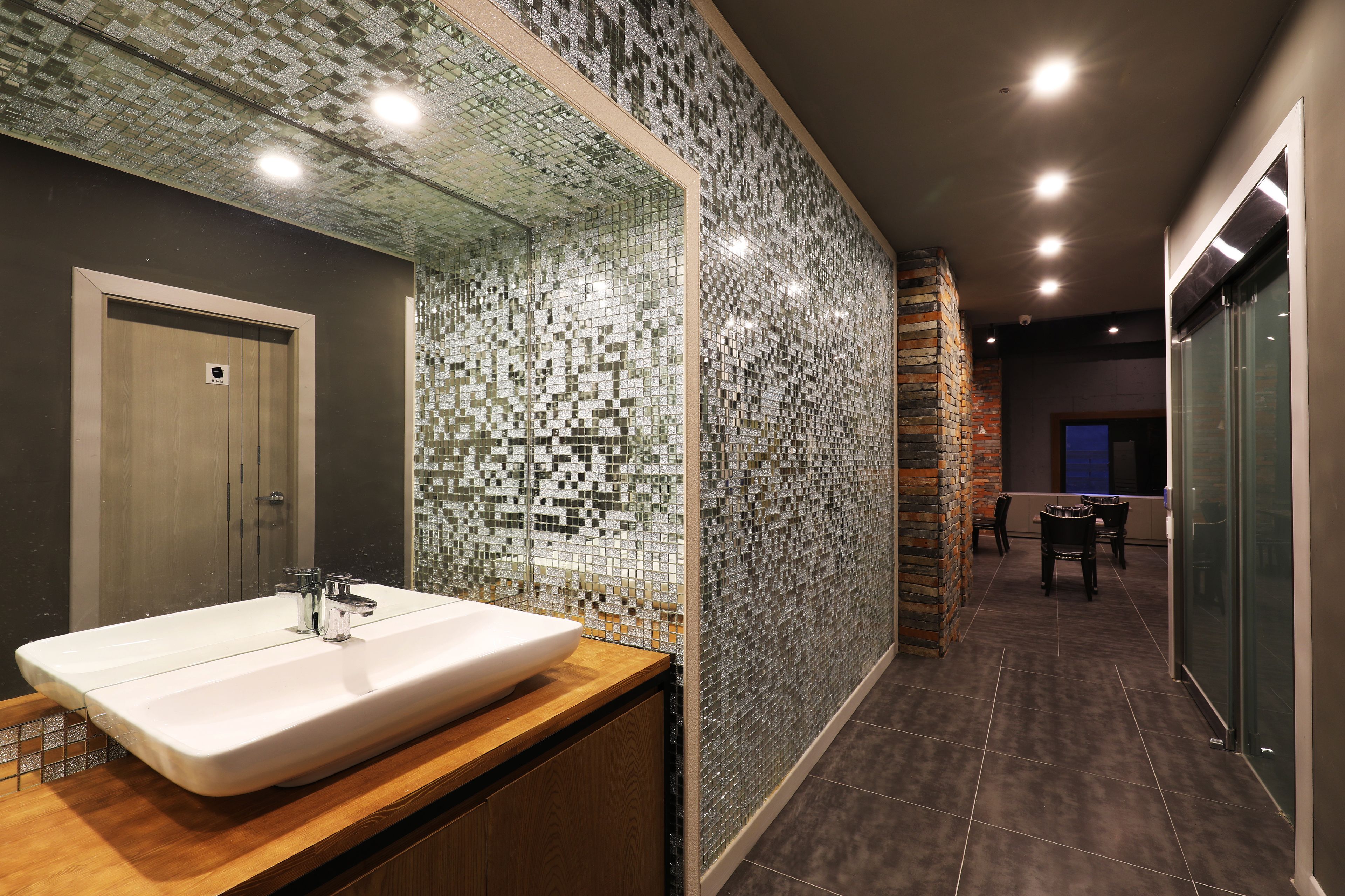 Un baño moderno con un lavabo grande, paredes con azulejos y un mueble de tocador de madera.