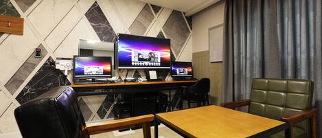 Una habitación moderna con una mesa y sillas de madera, un televisor de pantalla plana grande y un sillón de cuero verde.