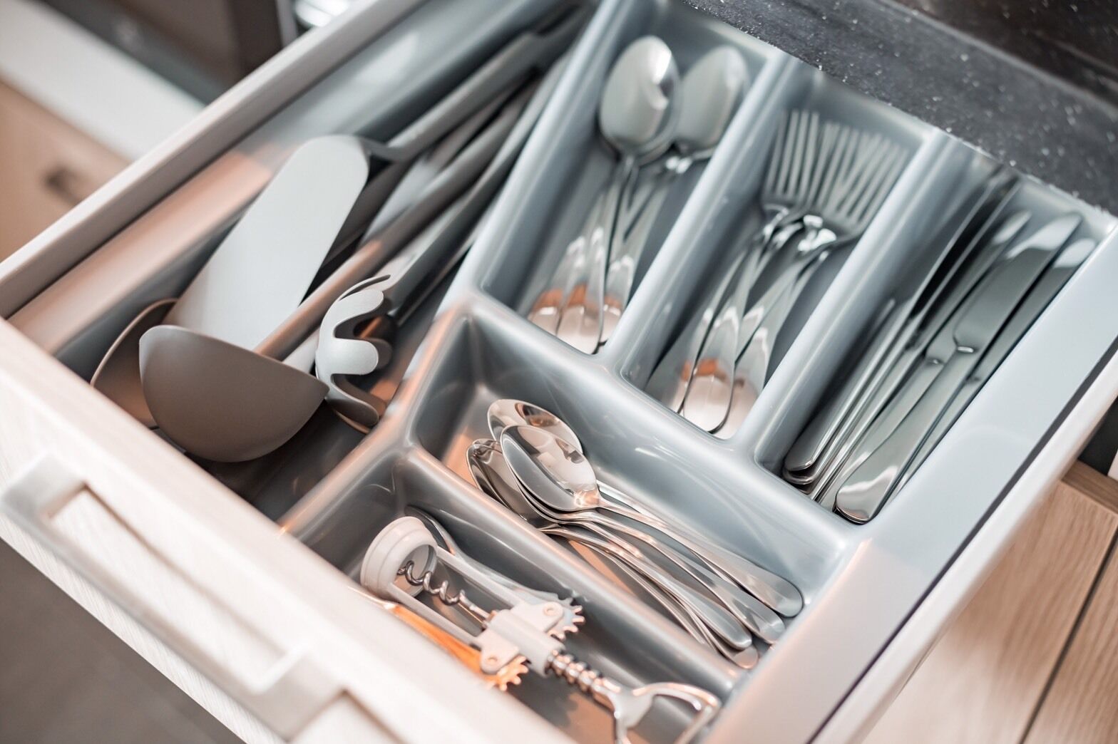 Un cajón con utensilios de cocina ordenados, como cucharas, tenedores y cuchillos.